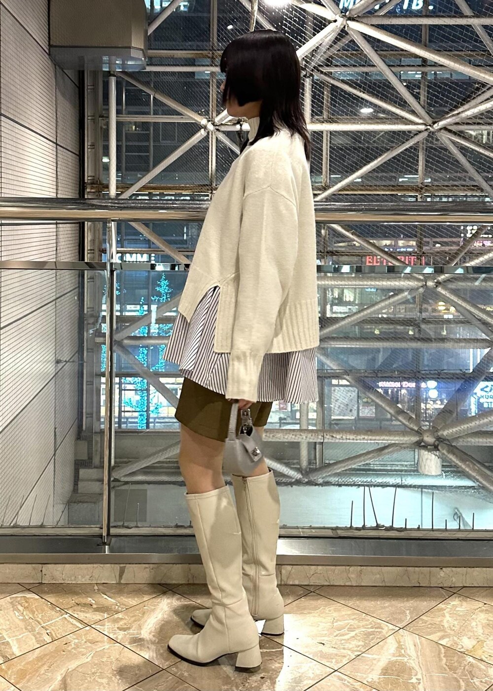 ホワイト系のニット/セーター、ブルー系のシャツ/ブラウス、イエロー系のスラックスを着用したレディースの冬コーディネートの3枚目の写真