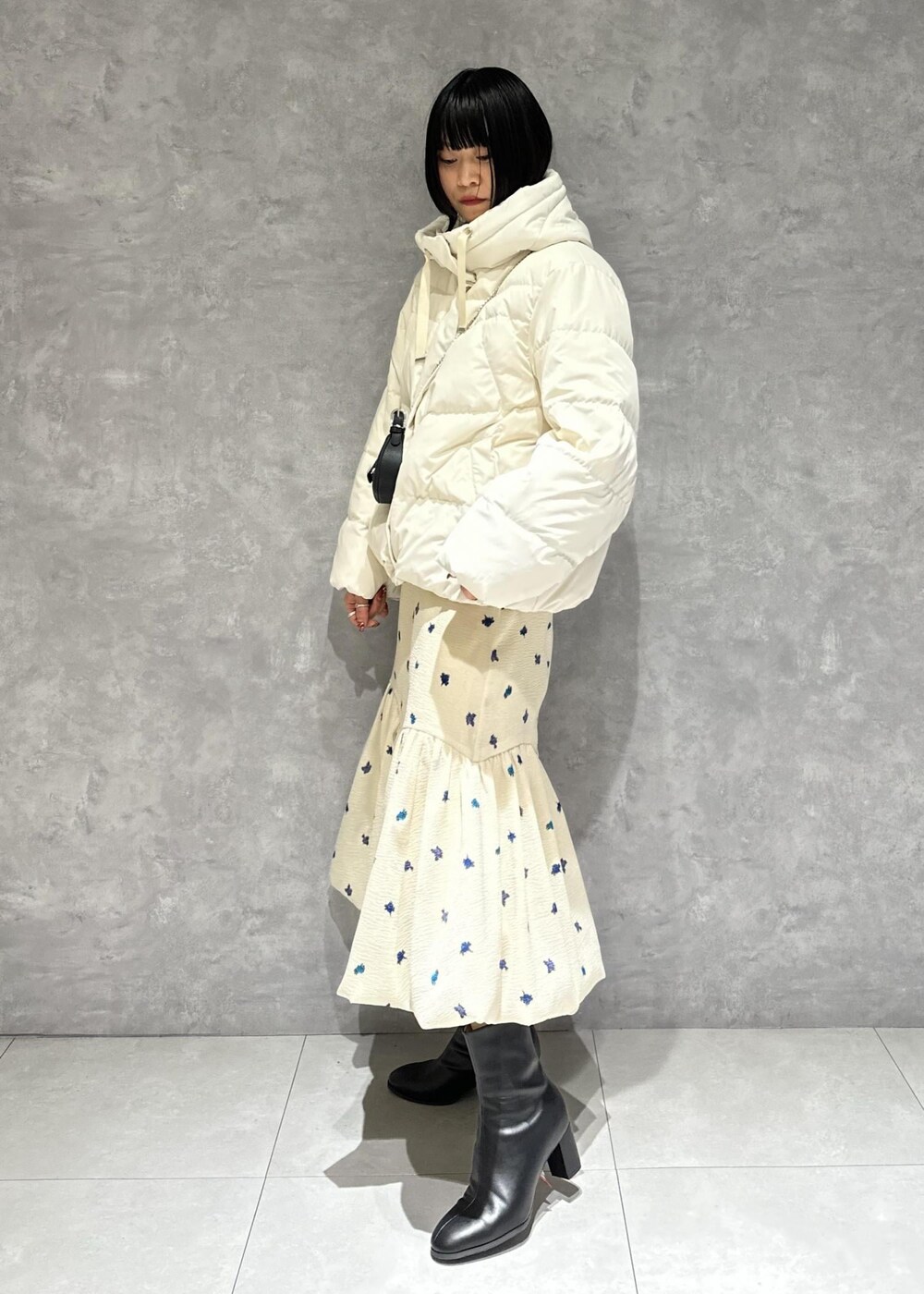 ブラック系のブーツ、ホワイト系のダウンジャケット/コート、ホワイト系のスカートを着用したレディースの冬コーディネートの2枚目の写真