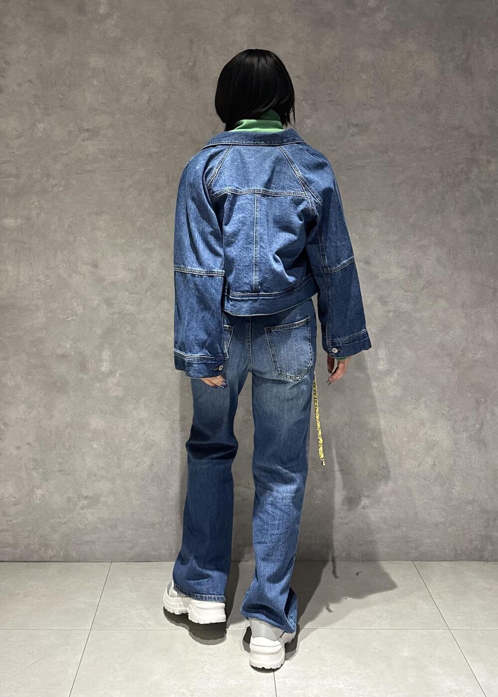 イエロー系のショルダーバッグ、シルバー系のスニーカー、グリーン系のワンピースを着用したレディースの春コーディネートの4枚目の写真