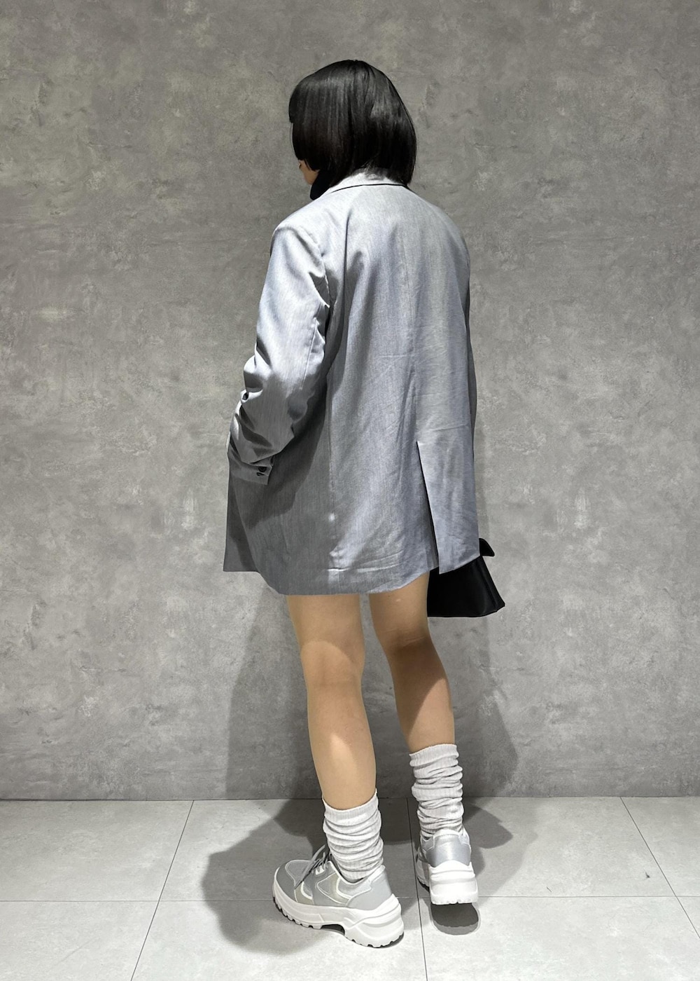 シルバー系のスニーカー、ホワイト系のブルゾン、グレー系のスラックスを着用したレディースの春コーディネートの4枚目の写真