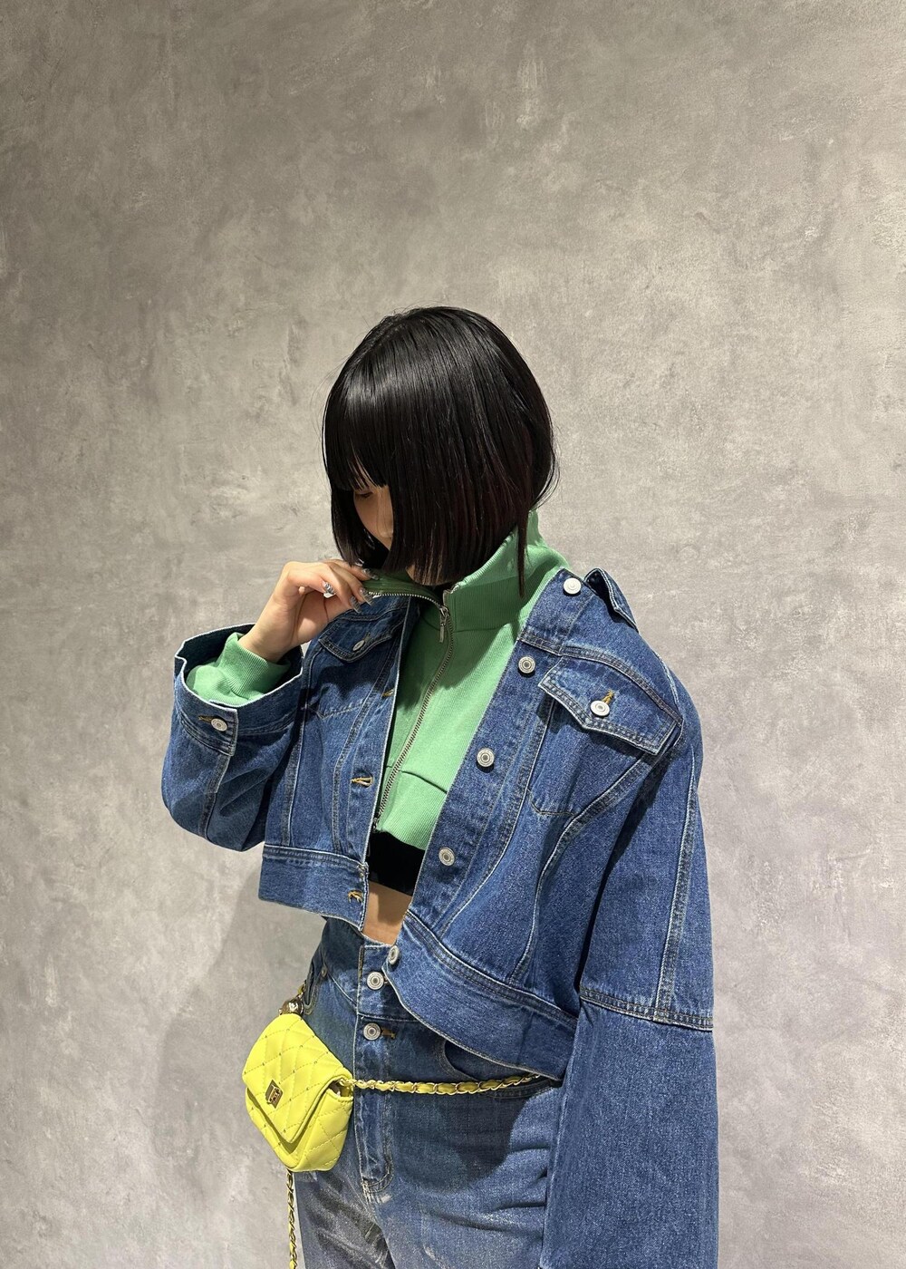 イエロー系のショルダーバッグ、シルバー系のスニーカー、グリーン系のワンピースを着用したレディースの春コーディネートの7枚目の写真