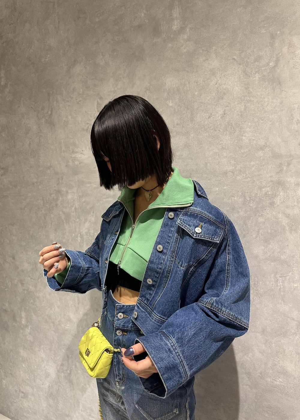 イエロー系のショルダーバッグ、シルバー系のスニーカー、グリーン系のワンピースを着用したレディースの春コーディネートの6枚目の写真