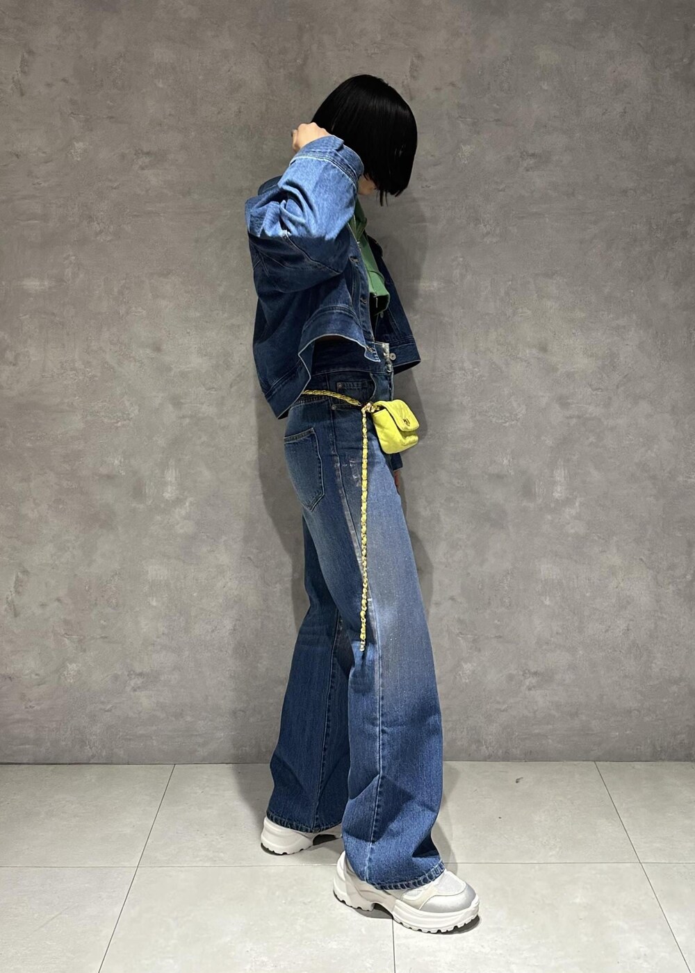 イエロー系のショルダーバッグ、シルバー系のスニーカー、グリーン系のワンピースを着用したレディースの春コーディネートの5枚目の写真