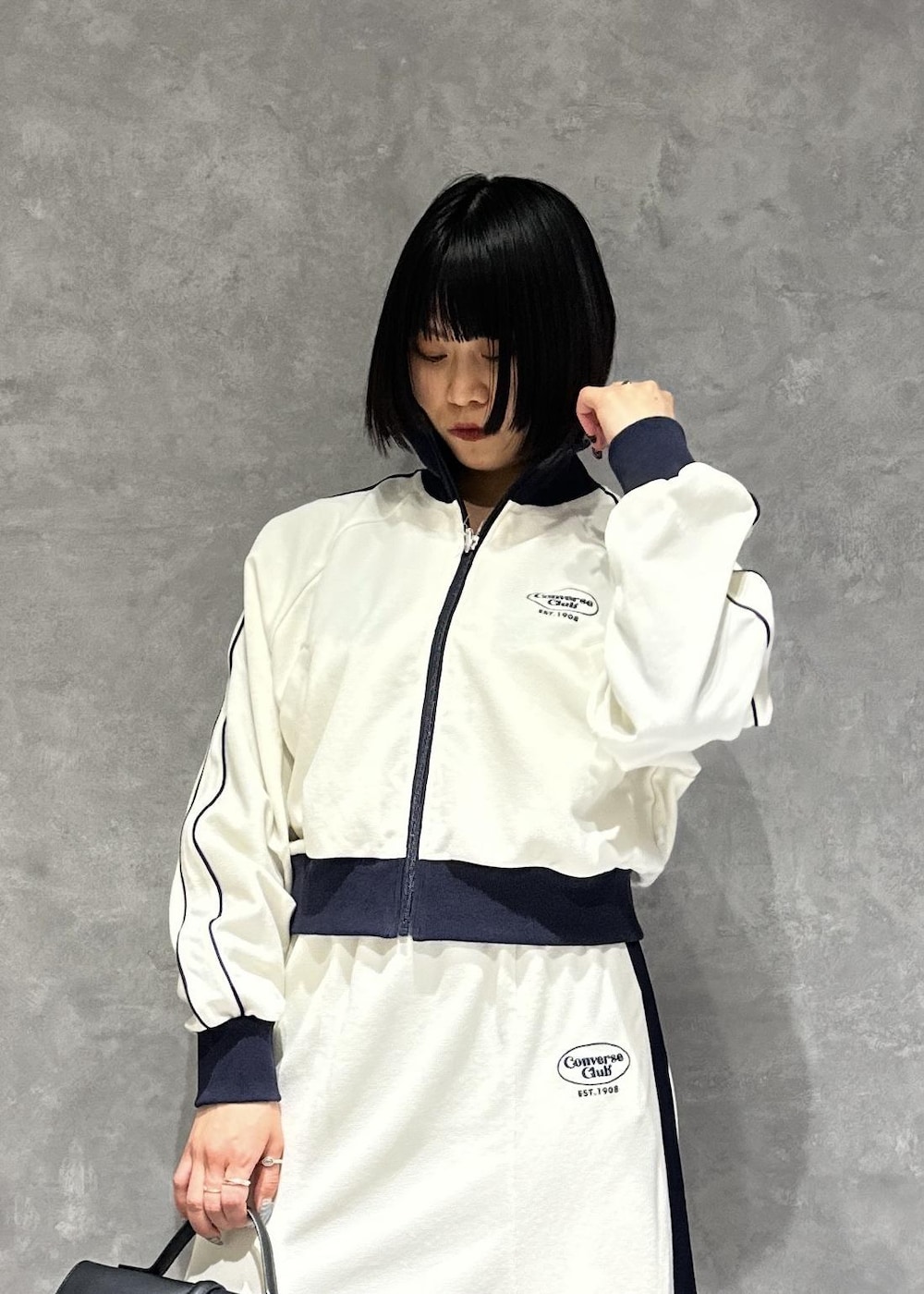 シルバー系のパンプス、ブラック系のショルダーバッグ、ホワイト系のブルゾンを着用したレディースの春コーディネートの5枚目の写真