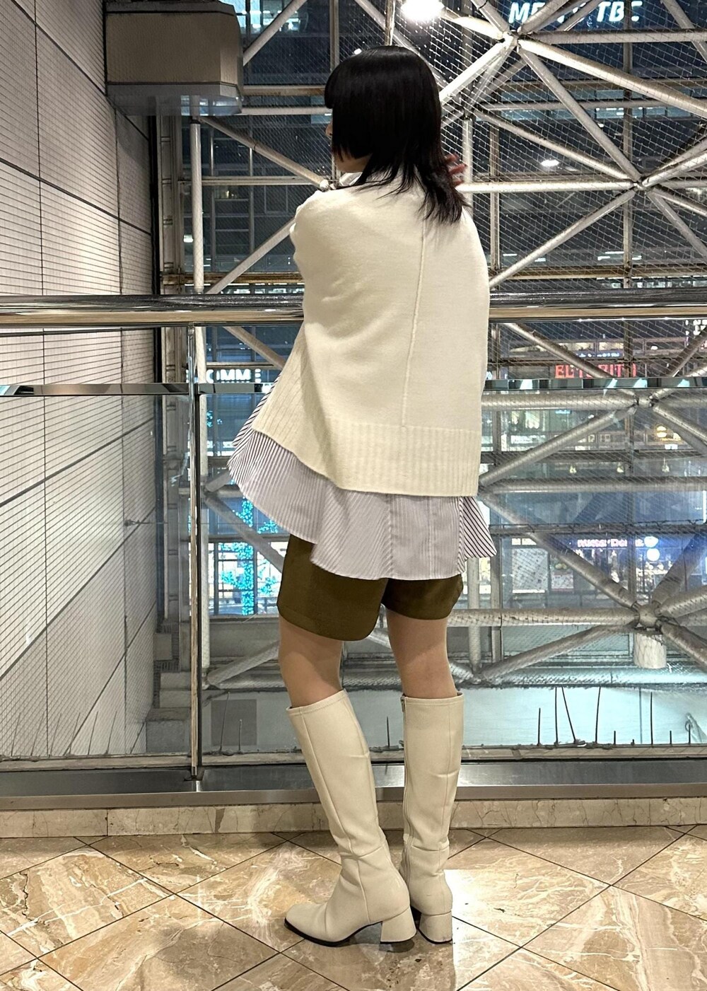 ホワイト系のニット/セーター、ブルー系のシャツ/ブラウス、イエロー系のスラックスを着用したレディースの冬コーディネートの4枚目の写真