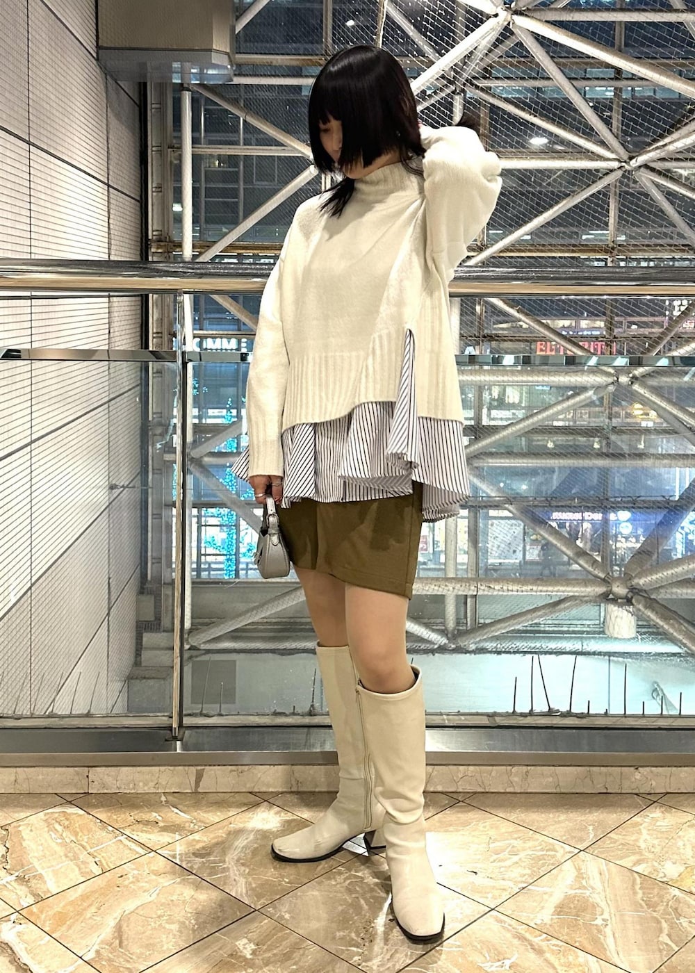 ホワイト系のニット/セーター、ブルー系のシャツ/ブラウス、イエロー系のスラックスを着用したレディースの冬コーディネートの2枚目の写真