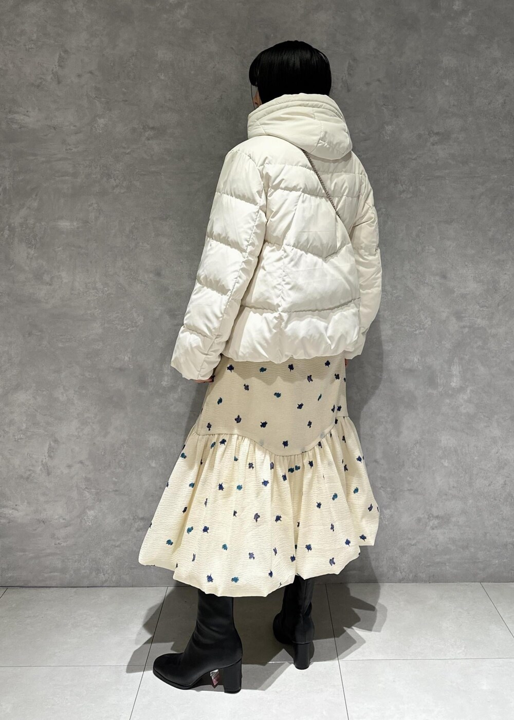 ブラック系のブーツ、ホワイト系のダウンジャケット/コート、ホワイト系のスカートを着用したレディースの冬コーディネートの3枚目の写真
