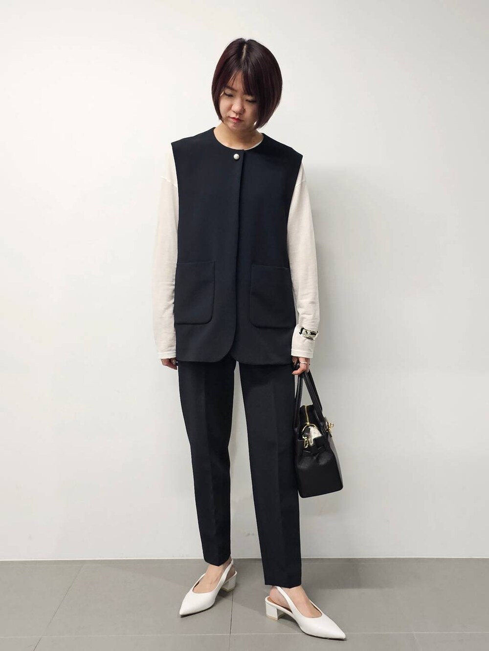 ホワイト系のTシャツ/カットソー、ブラック系のベスト、ブラック系のその他パンツを着用したレディースの冬コーディネートの5枚目の写真