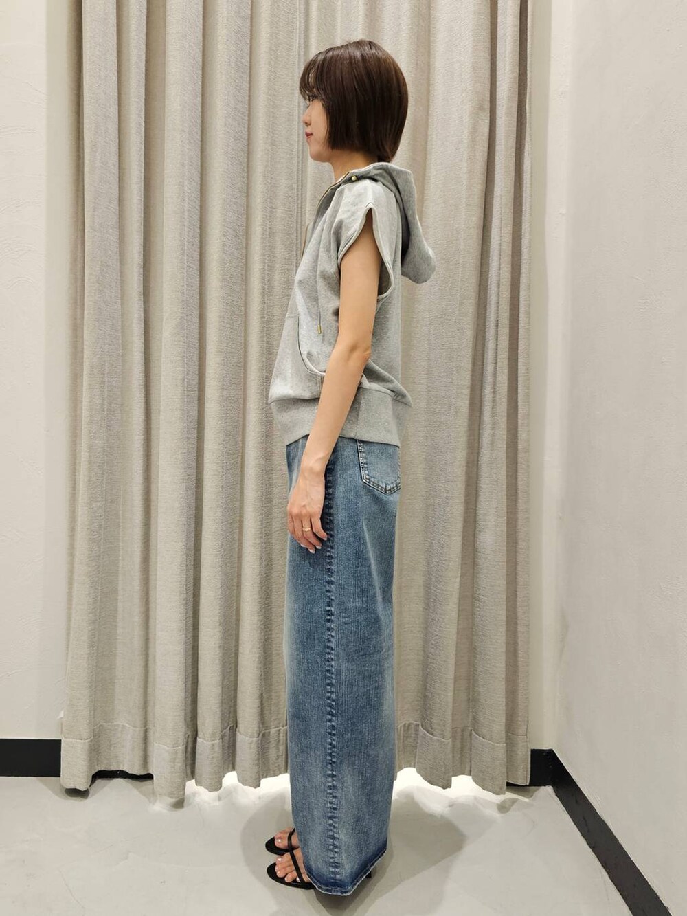 ブラック系のスリッポン、ブルー系のデニムパンツ、グレー系のパーカーを着用したレディースの夏コーディネートの3枚目の写真