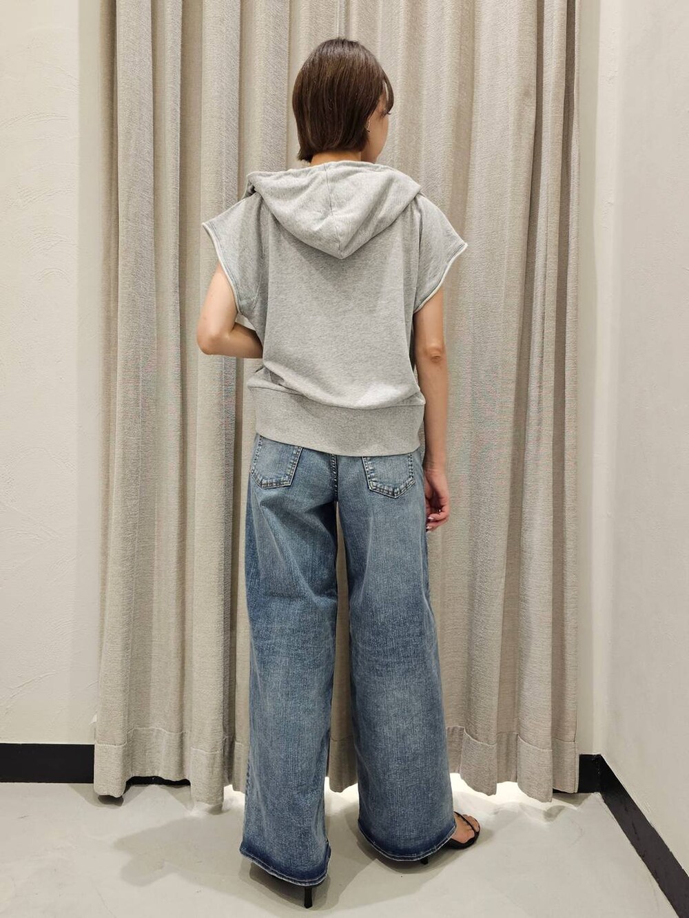 ブラック系のスリッポン、ブルー系のデニムパンツ、グレー系のパーカーを着用したレディースの夏コーディネートの4枚目の写真