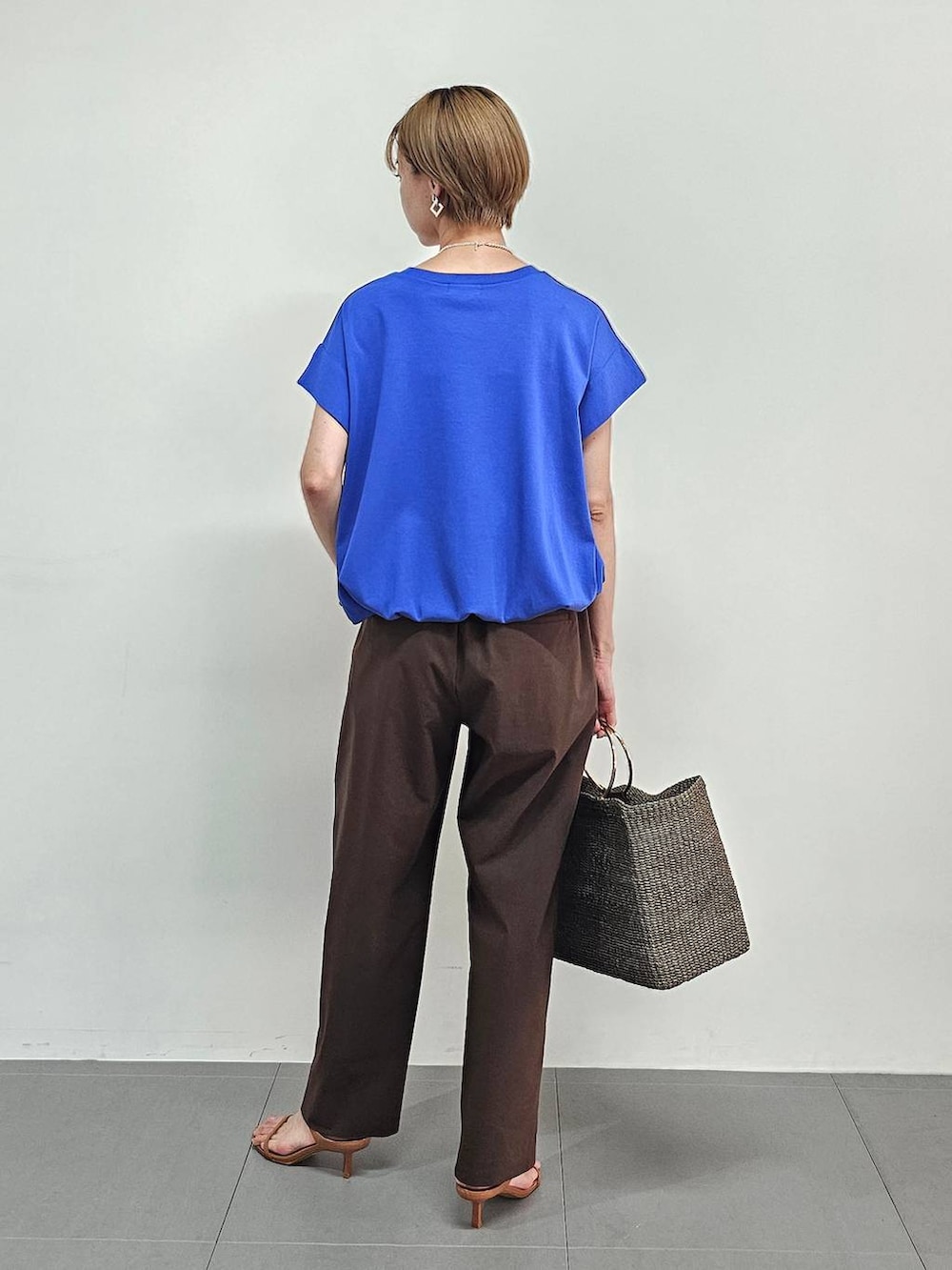 ブラウン系のかごバッグ、ブルー系のTシャツ/カットソー、ブラウン系のサンダルを着用したレディースの夏コーディネートの3枚目の写真