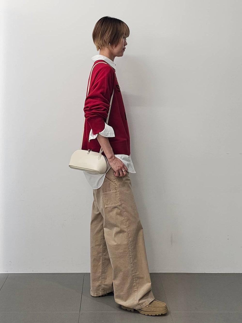 ホワイト系のショルダーバッグ、ホワイト系のシャツ/ブラウス、ベージュ系のチノパンツを着用したレディースの秋コーディネートの3枚目の写真