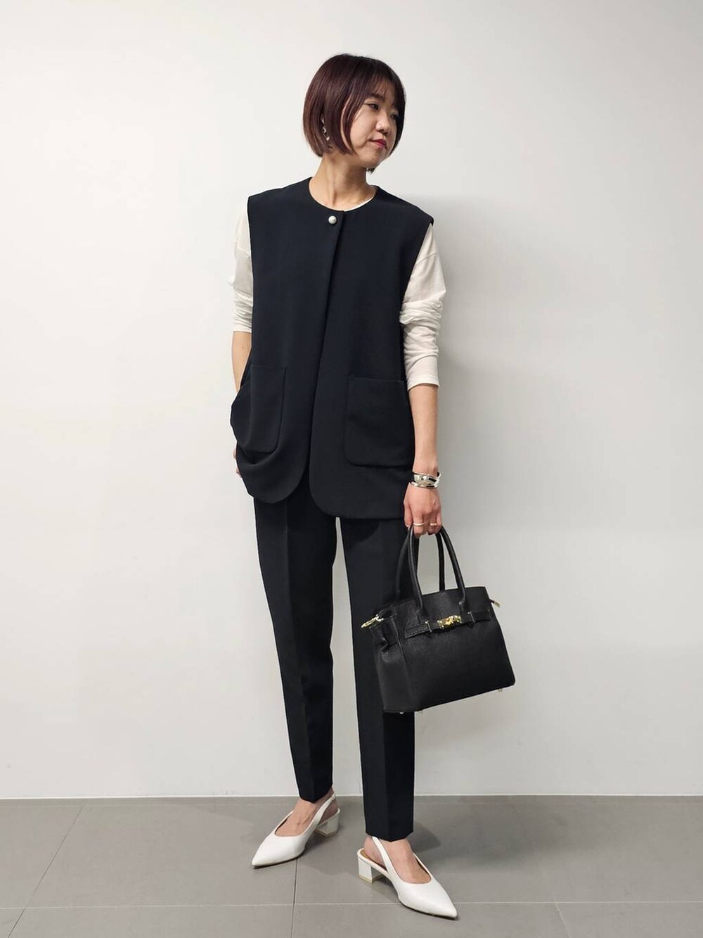 ホワイト系のTシャツ/カットソー、ブラック系のベスト、ブラック系のその他パンツを着用したレディースの冬コーディネートの4枚目の写真