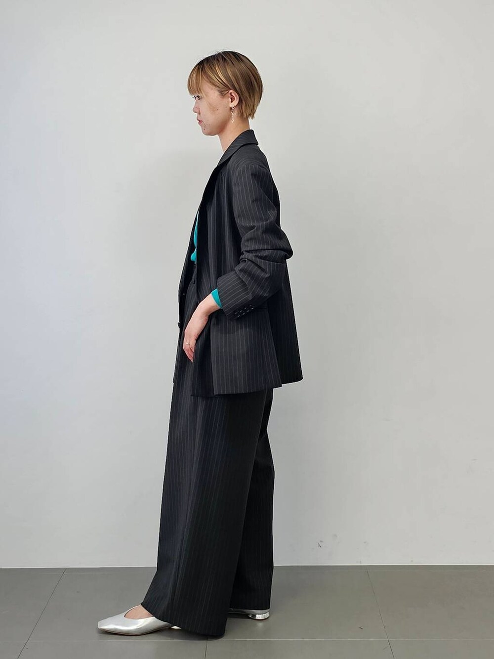 その他のパンプス、ブラック系のハンドバッグ、グリーン系のニット/セーターを着用したレディースの夏コーディネートの2枚目の写真