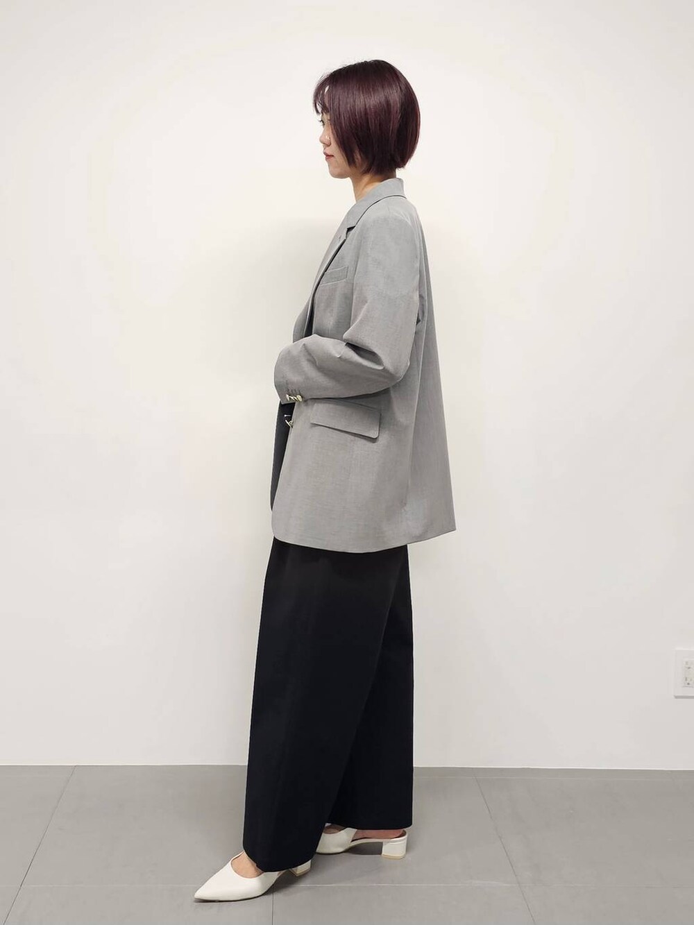ブラック系のつなぎ/オールインワン、グレー系のテーラードジャケット、ホワイト系のパンプスを着用したレディースの冬コーディネートの2枚目の写真