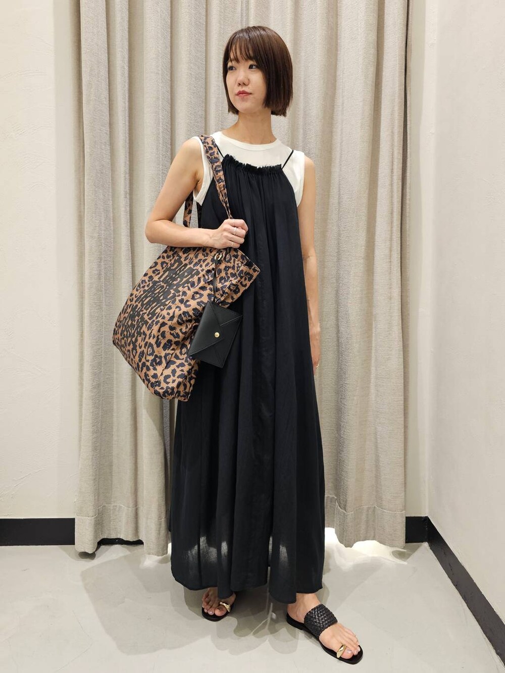 ブラック系のサンダル、ブラック系のワンピース、ホワイト系のTシャツ/カットソーを着用したレディースの夏コーディネートの5枚目の写真