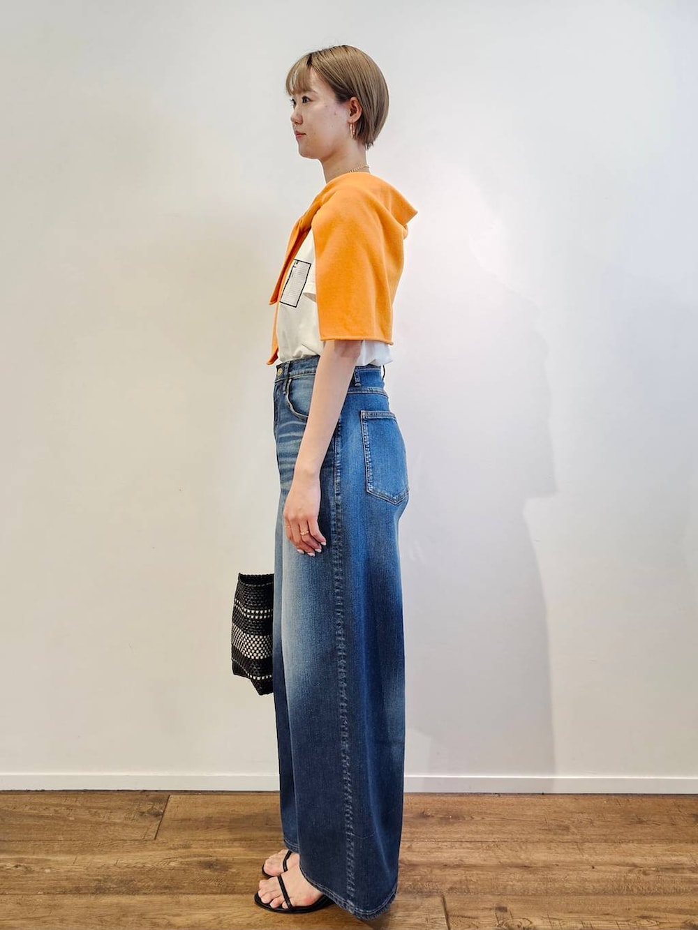 ブルー系のデニムパンツ、ブラック系のサンダル、その他のトートバッグを着用したレディースの春コーディネートの2枚目の写真