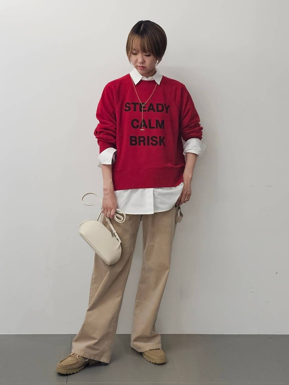 ホワイト系のショルダーバッグ、ホワイト系のシャツ/ブラウス、ベージュ系のチノパンツを着用したレディースの秋コーディネートの5枚目の写真