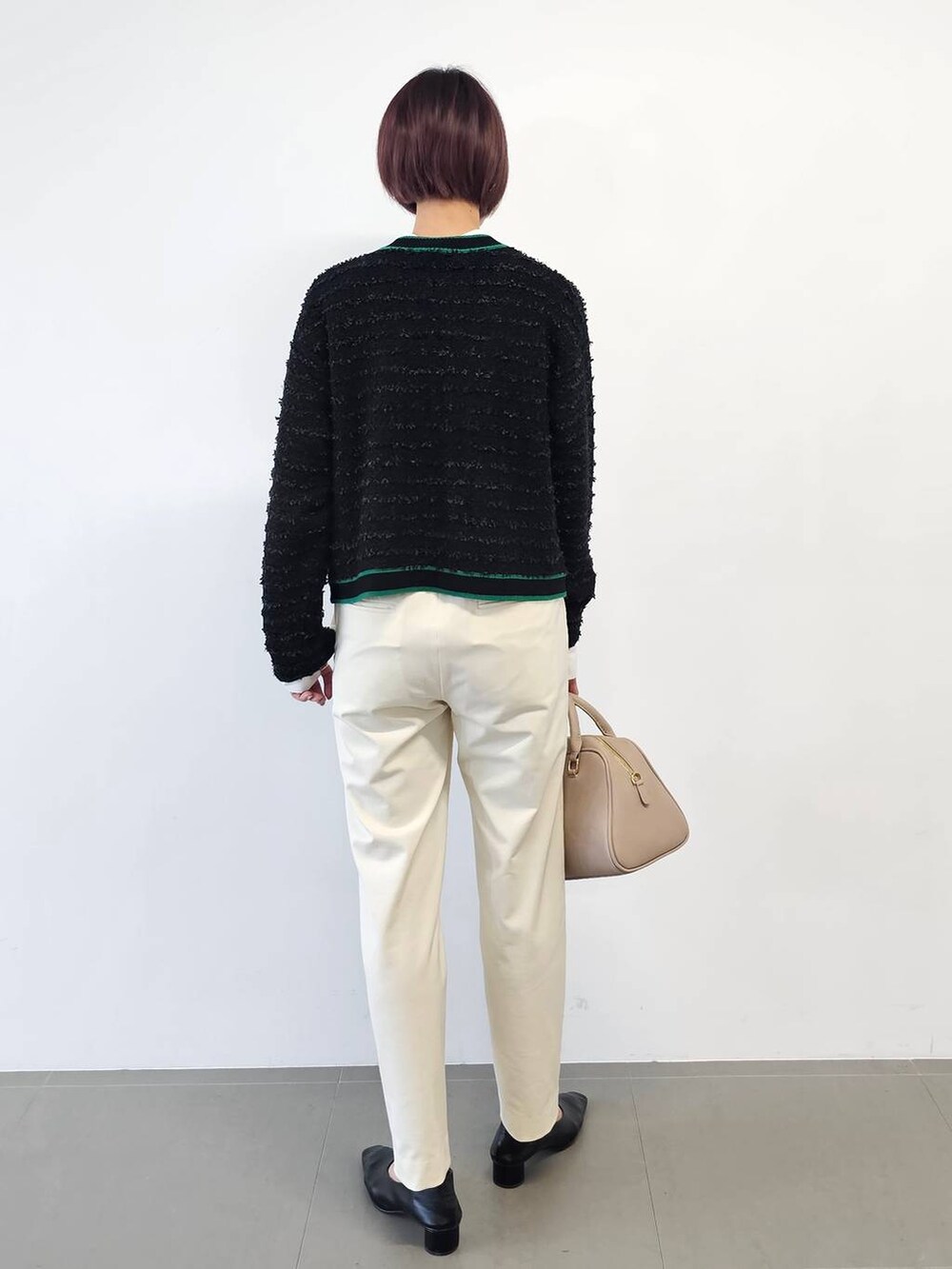 ベージュ系のボストンバッグ、ブラック系のパンプス、ホワイト系のその他パンツを着用したレディースの冬コーディネートの4枚目の写真