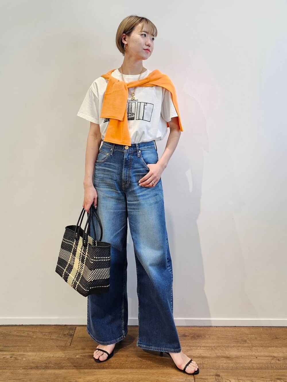 ブルー系のデニムパンツ、ブラック系のサンダル、その他のトートバッグを着用したレディースの春コーディネートの4枚目の写真