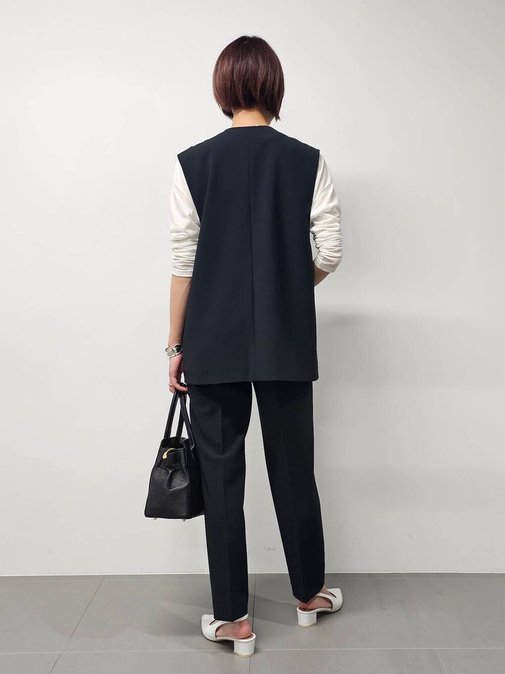 ホワイト系のTシャツ/カットソー、ブラック系のベスト、ブラック系のその他パンツを着用したレディースの冬コーディネートの3枚目の写真