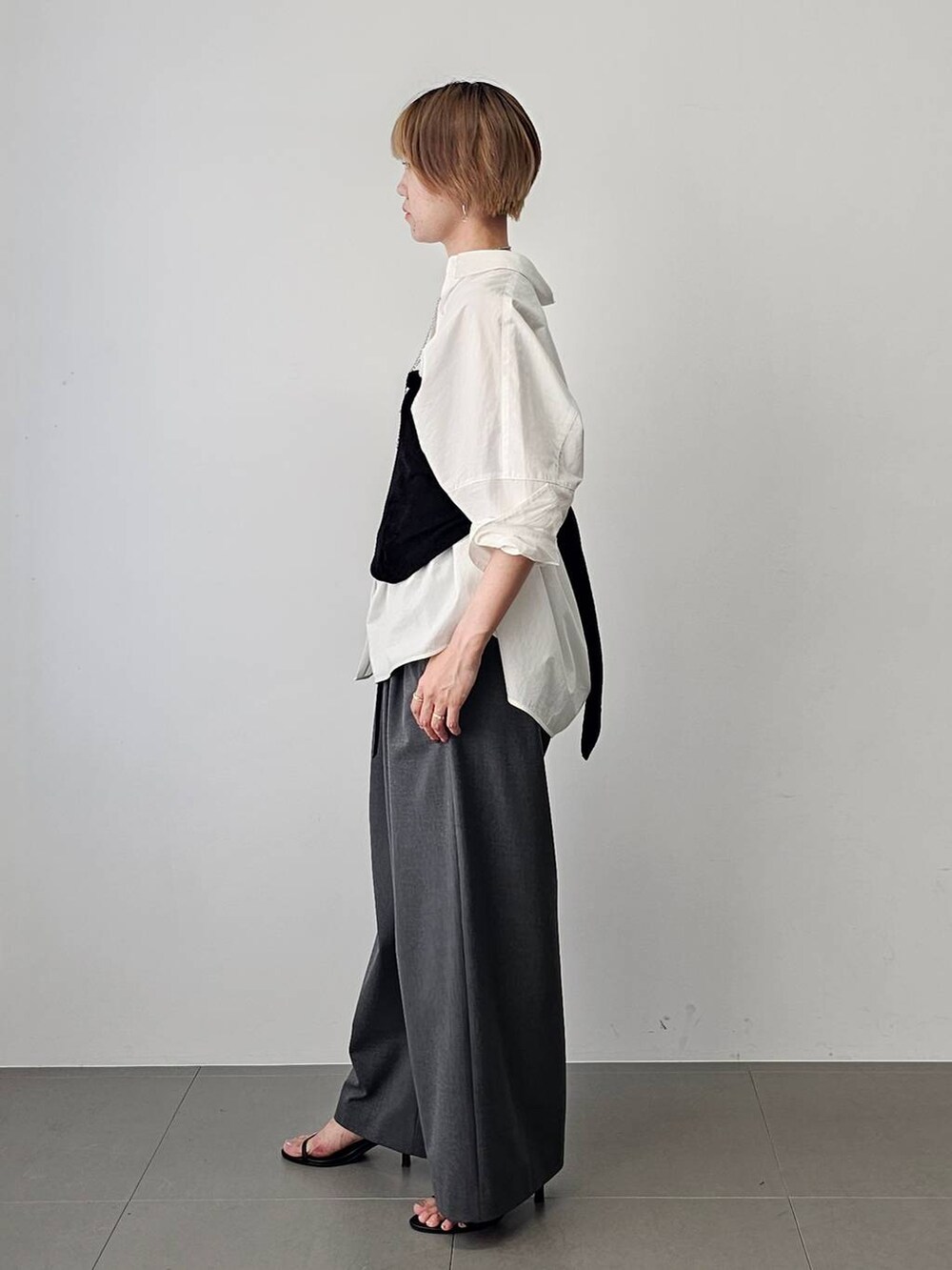 ブラック系のショルダーバッグ、ブラック系のサンダル、ホワイト系のシャツ/ブラウスを着用したレディースの夏コーディネートの5枚目の写真