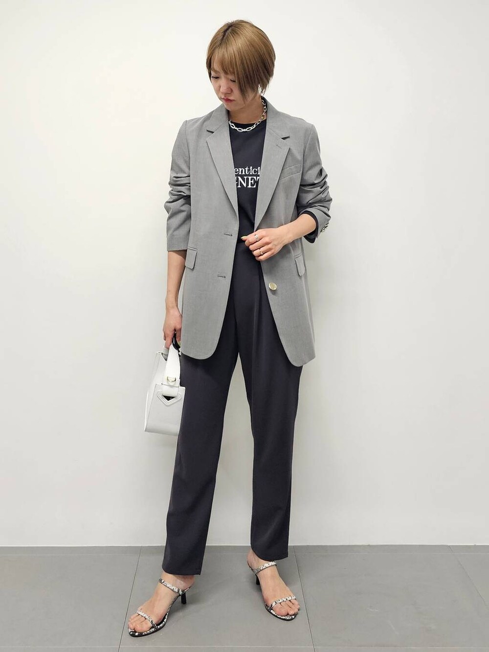 ホワイト系のハンドバッグ、グレー系のTシャツ/カットソー、グレー系のスラックスを着用したレディースの冬コーディネートの5枚目の写真