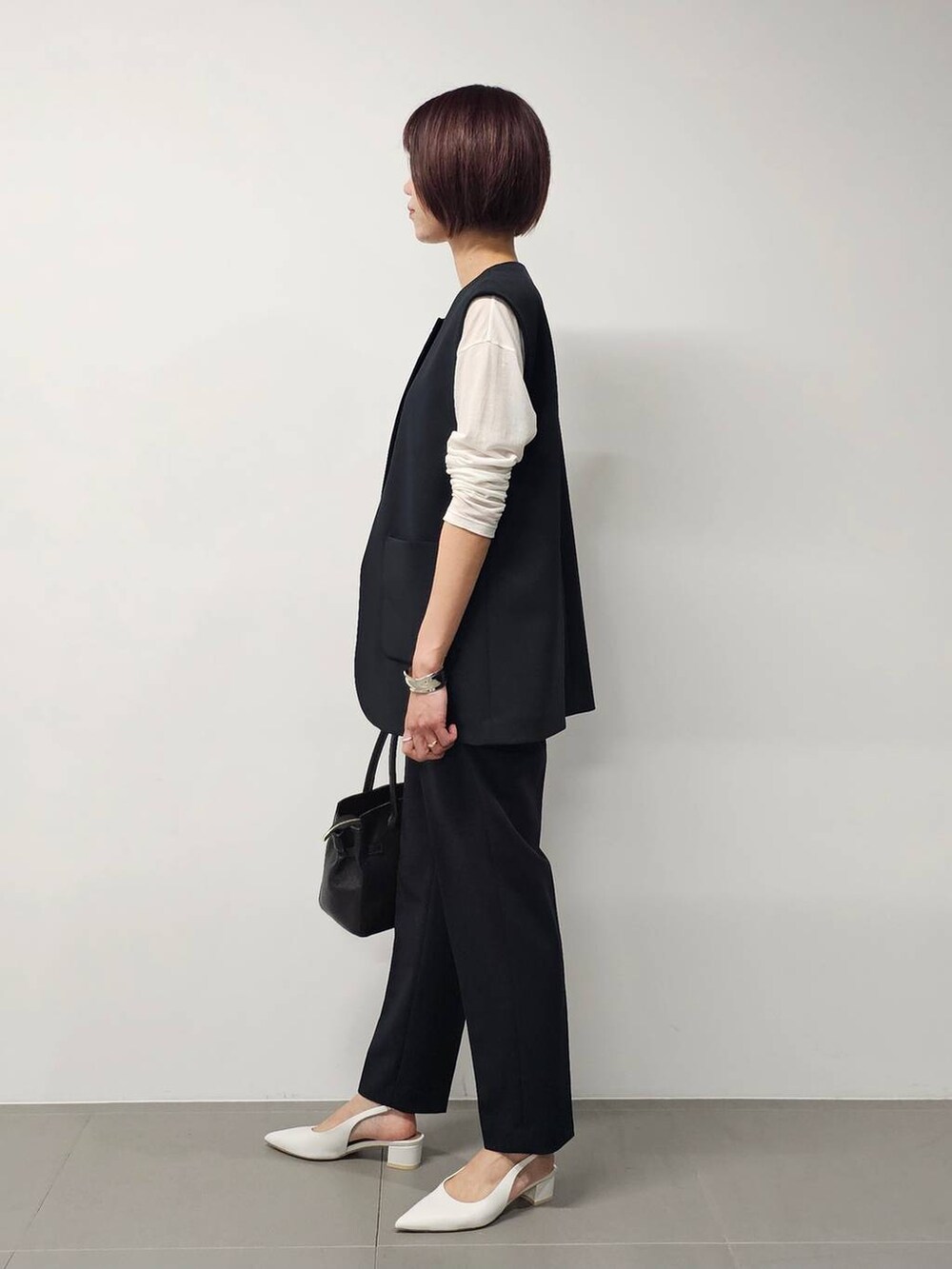 ホワイト系のTシャツ/カットソー、ブラック系のベスト、ブラック系のその他パンツを着用したレディースの冬コーディネートの2枚目の写真