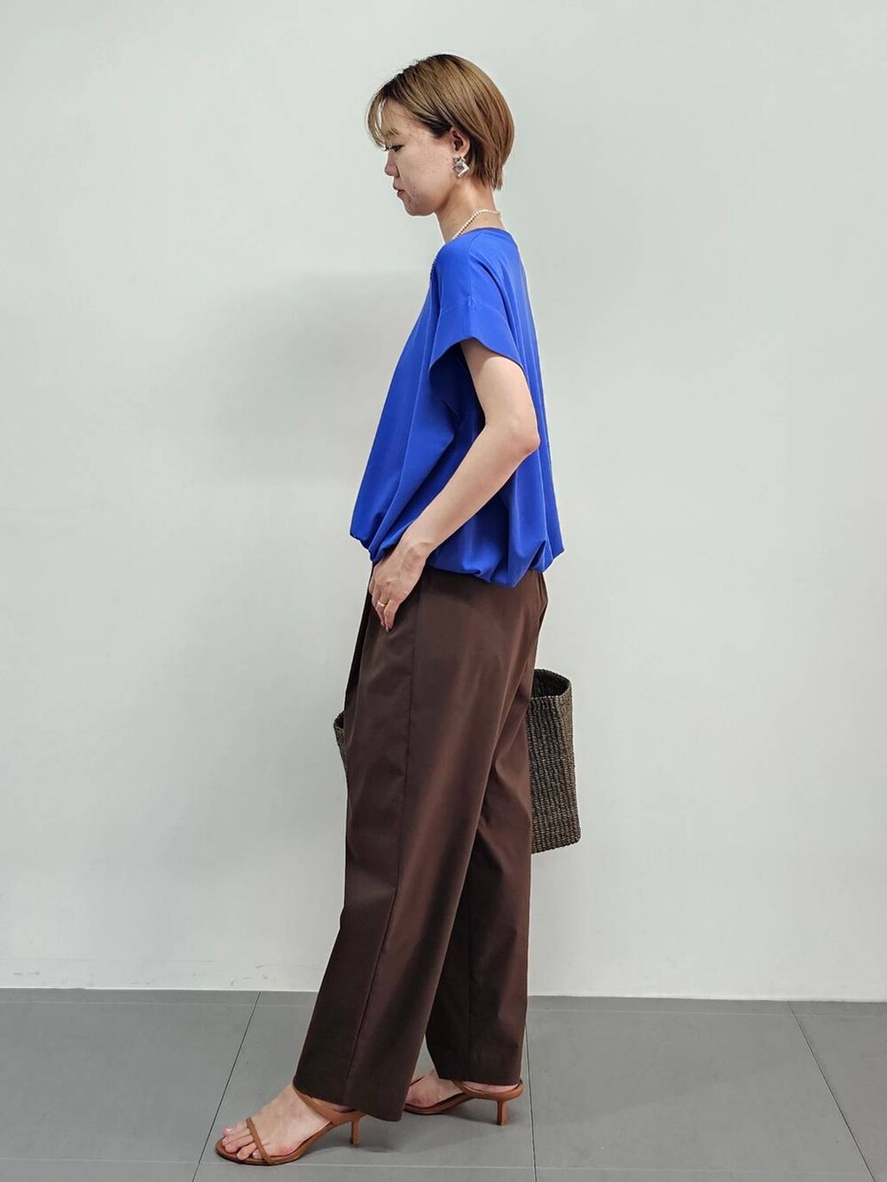 ブラウン系のかごバッグ、ブルー系のTシャツ/カットソー、ブラウン系のサンダルを着用したレディースの夏コーディネートの4枚目の写真