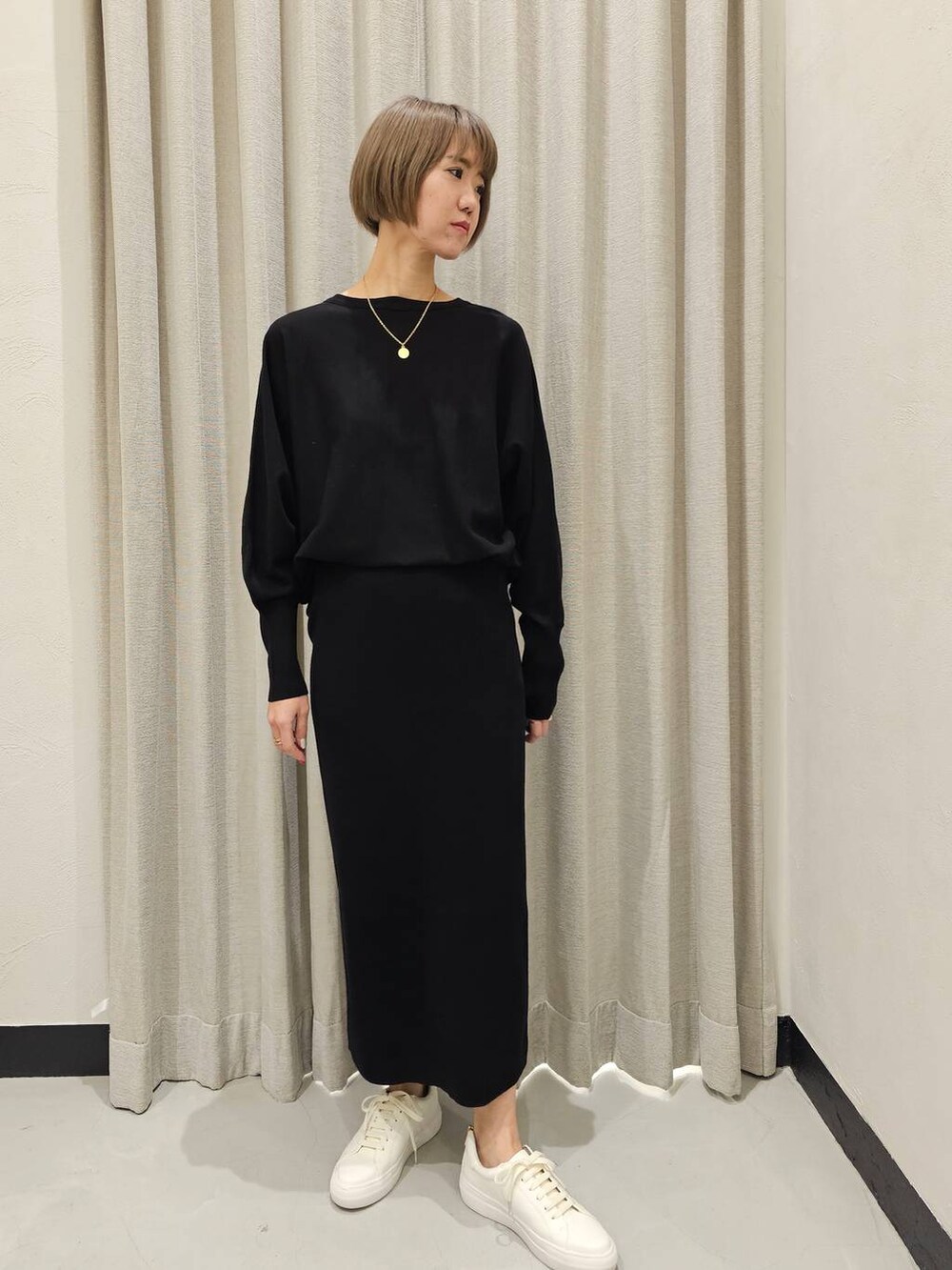 ブラック系のTシャツ/カットソー、ブラック系のスカート、ホワイト系のスニーカーを着用したレディースの冬コーディネートの2枚目の写真