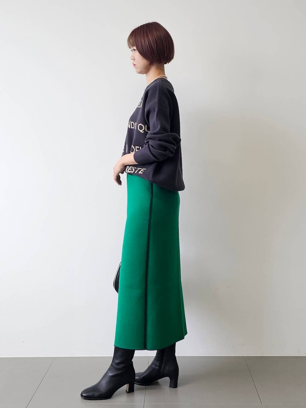 ブラック系のトートバッグ、ブラック系のブーツ、ブルー系のニット/セーターを着用したレディースの秋コーディネートの2枚目の写真