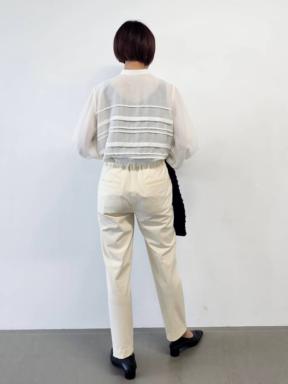 ベージュ系のボストンバッグ、ブラック系のパンプス、ホワイト系のその他パンツを着用したレディースの冬コーディネートの6枚目の写真