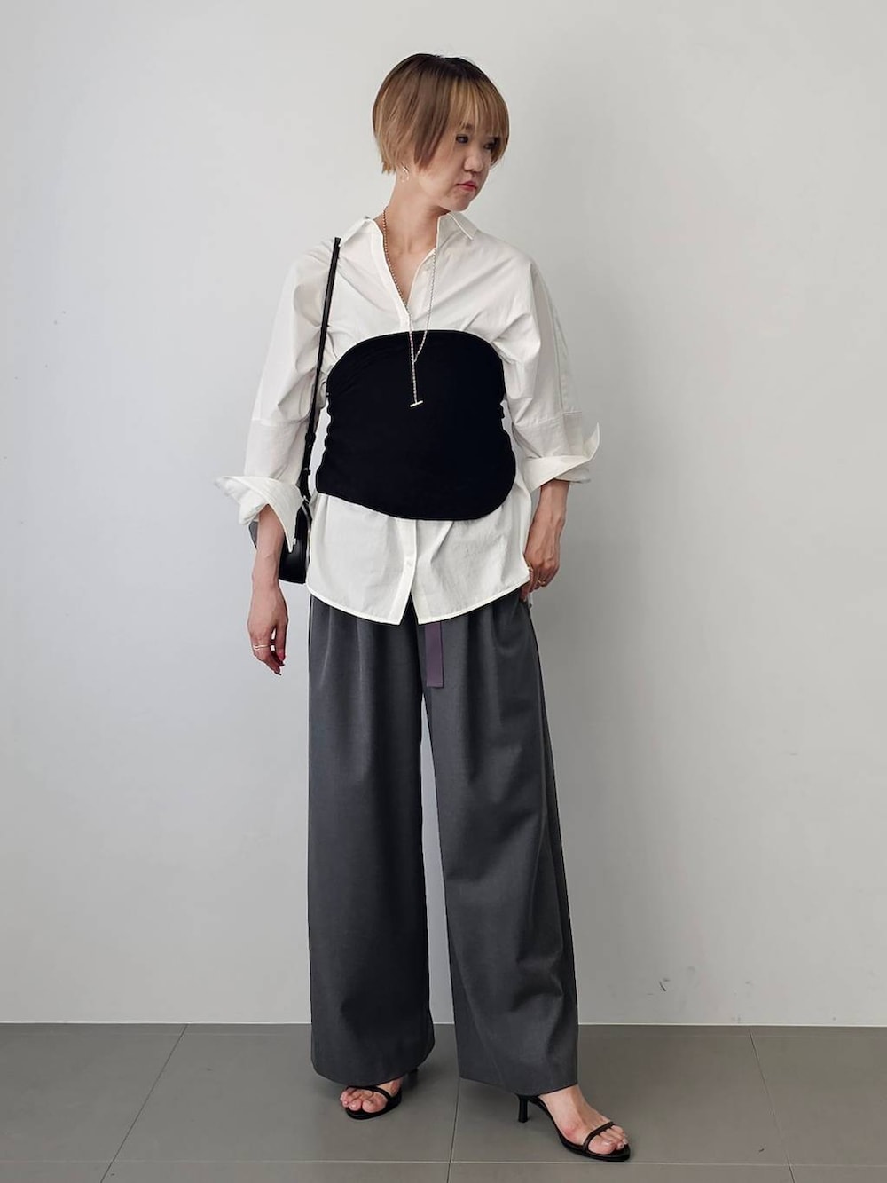 ブラック系のショルダーバッグ、ブラック系のサンダル、ホワイト系のシャツ/ブラウスを着用したレディースの夏コーディネートの3枚目の写真