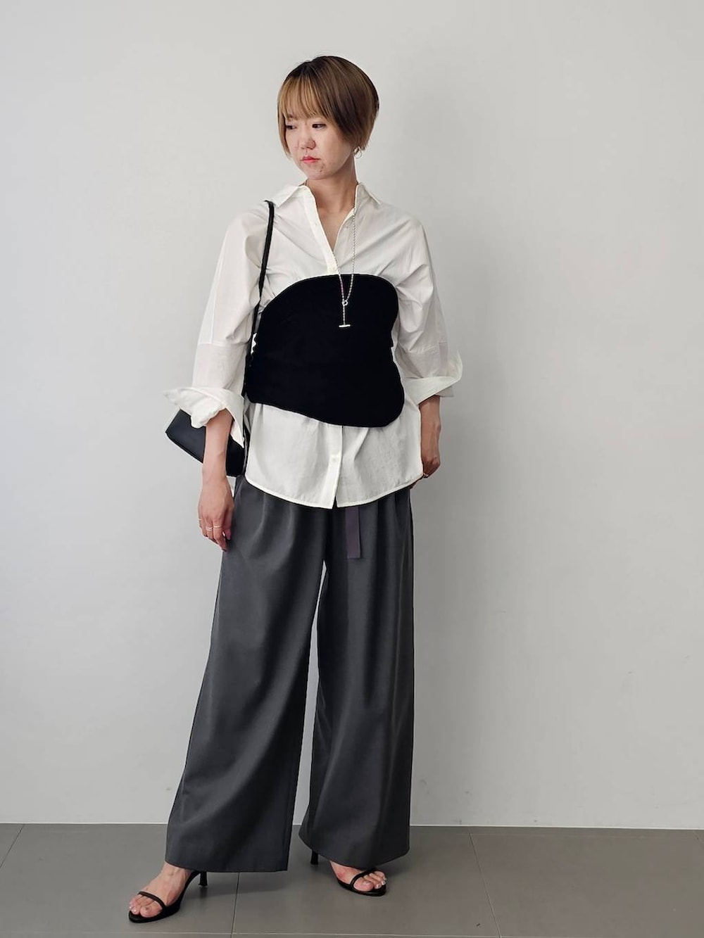 ブラック系のショルダーバッグ、ブラック系のサンダル、ホワイト系のシャツ/ブラウスを着用したレディースの夏コーディネートの2枚目の写真