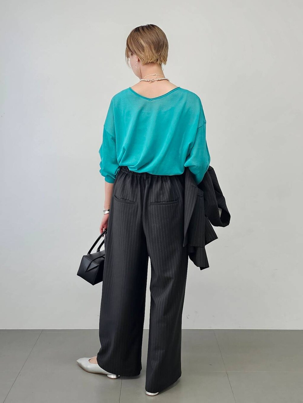 その他のパンプス、ブラック系のハンドバッグ、グリーン系のニット/セーターを着用したレディースの夏コーディネートの5枚目の写真