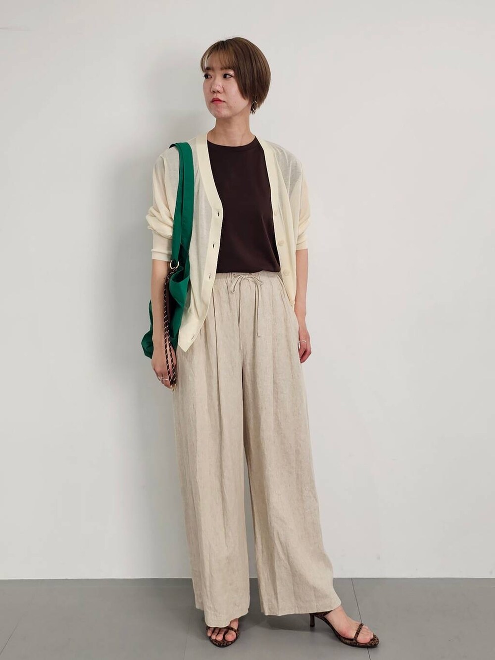 ホワイト系のカーディガン/ボレロ、ベージュ系のその他パンツ、ブラウン系のTシャツ/カットソーを着用したレディースの春コーディネートの2枚目の写真