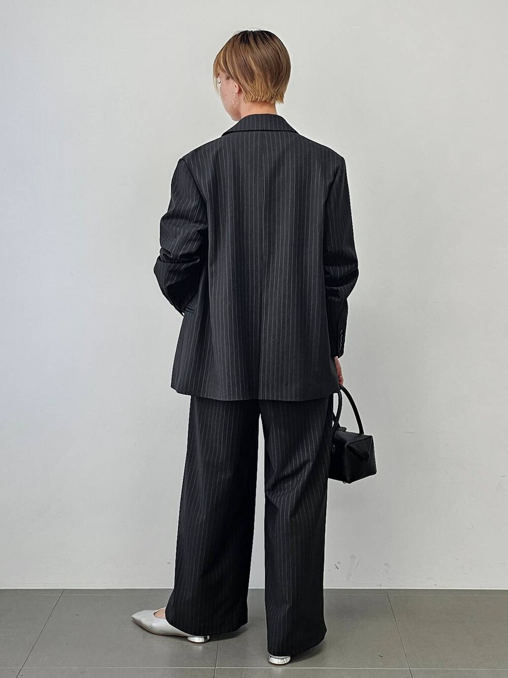 その他のパンプス、ブラック系のハンドバッグ、グリーン系のニット/セーターを着用したレディースの夏コーディネートの3枚目の写真