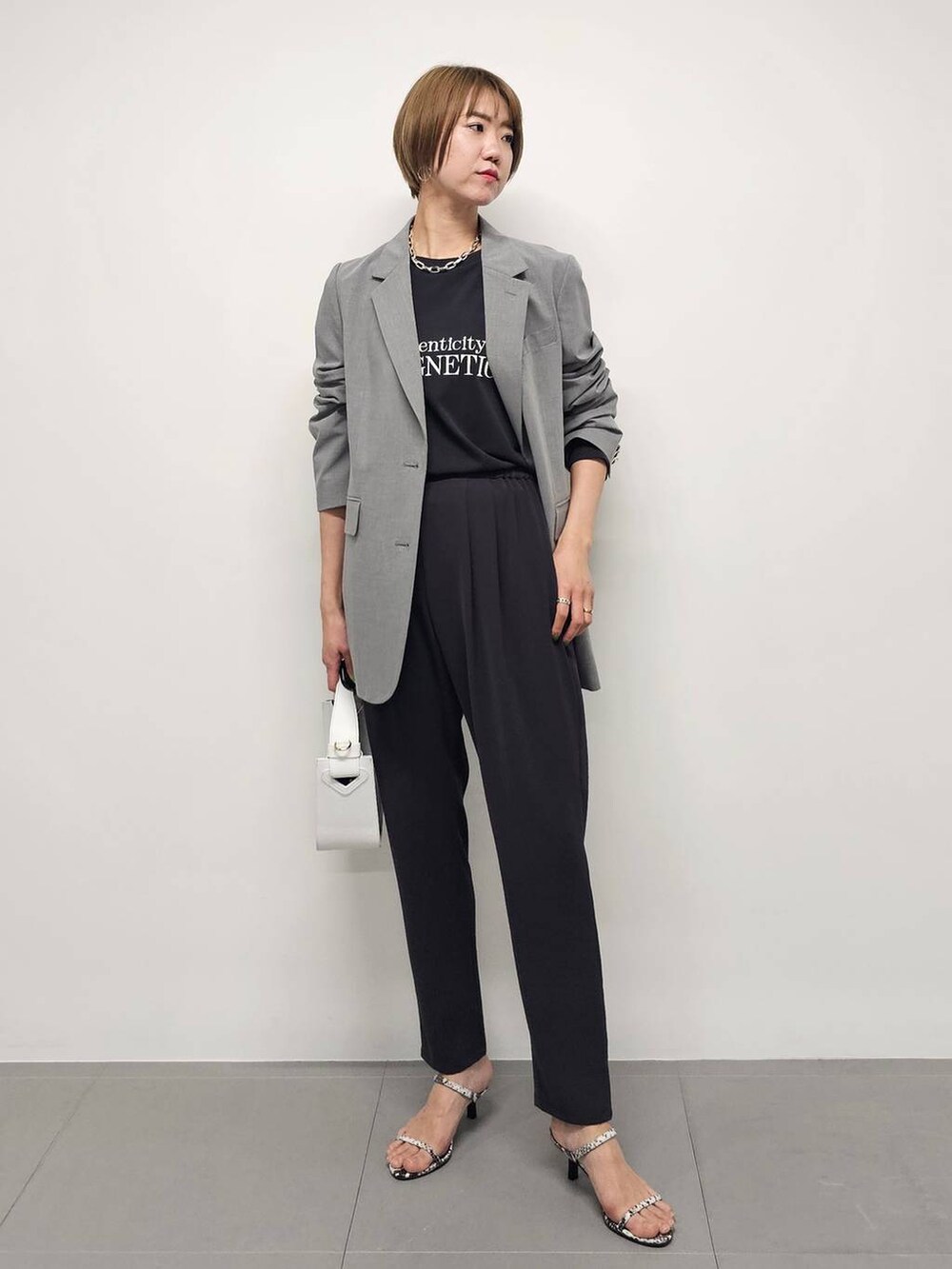 ホワイト系のハンドバッグ、グレー系のTシャツ/カットソー、グレー系のスラックスを着用したレディースの冬コーディネートの2枚目の写真