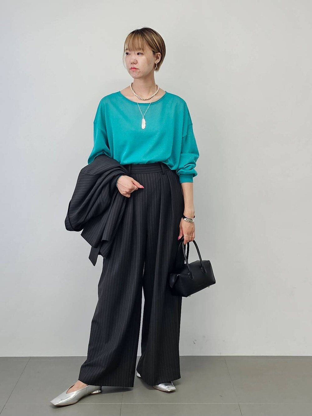 その他のパンプス、ブラック系のハンドバッグ、グリーン系のニット/セーターを着用したレディースの夏コーディネートの4枚目の写真