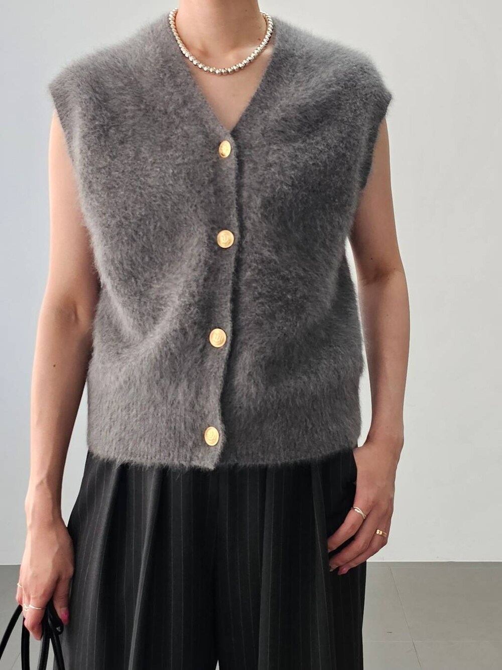 その他のパンプス、ブラック系のトートバッグ、グレー系のスラックスを着用したレディースの夏コーディネートの2枚目の写真