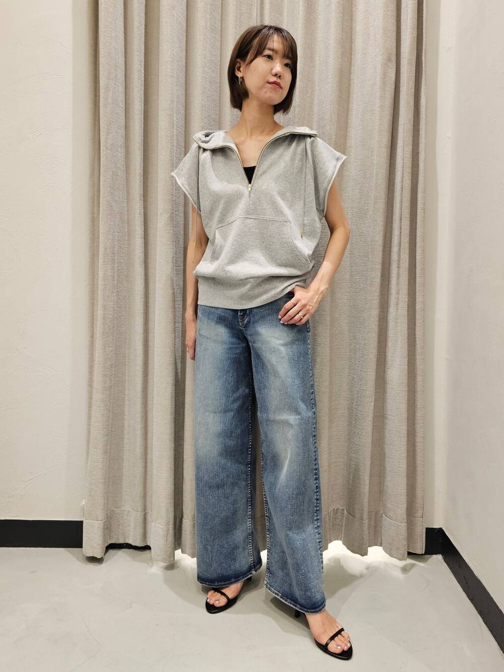 ブラック系のスリッポン、ブルー系のデニムパンツ、グレー系のパーカーを着用したレディースの夏コーディネートの5枚目の写真