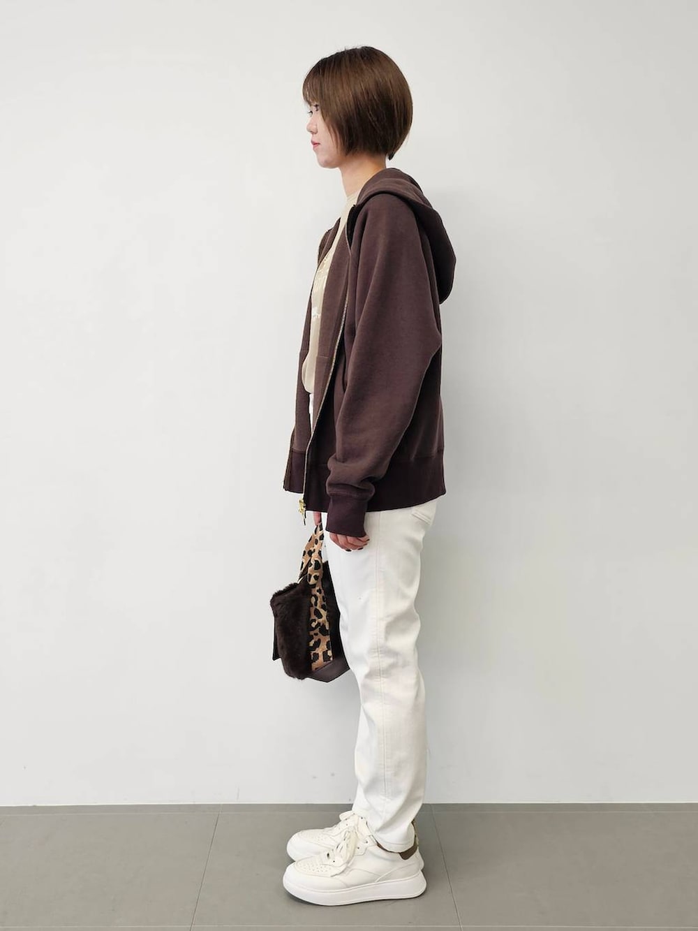 ホワイト系のデニムパンツ、ベージュ系のTシャツ/カットソー、ホワイト系のスニーカーを着用したレディースの秋コーディネートの2枚目の写真