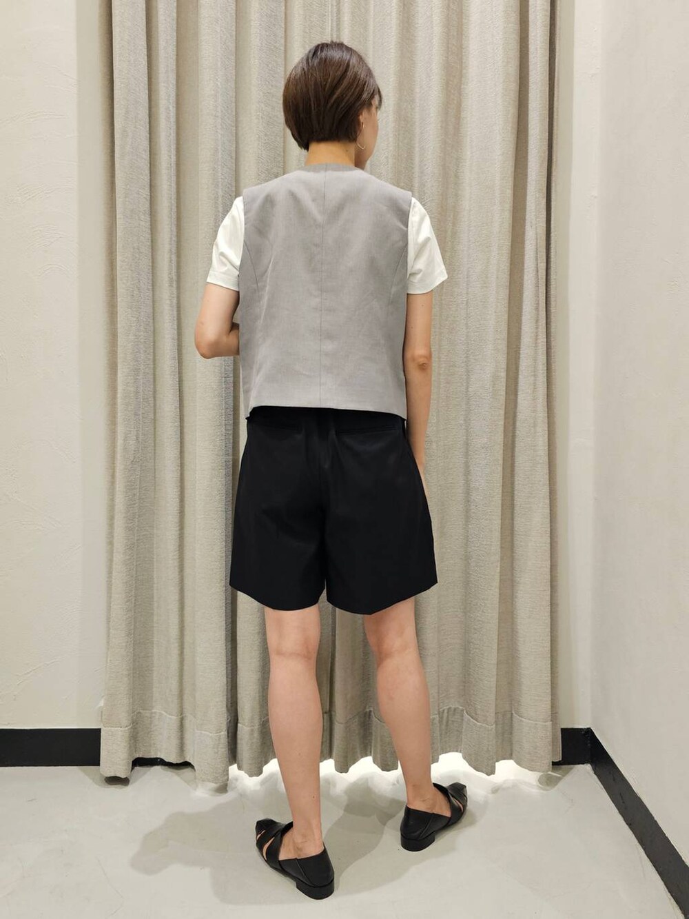 グレー系のベスト、ブラック系のチノパンツ、ブラック系のパンプスを着用したレディースの夏コーディネートの3枚目の写真