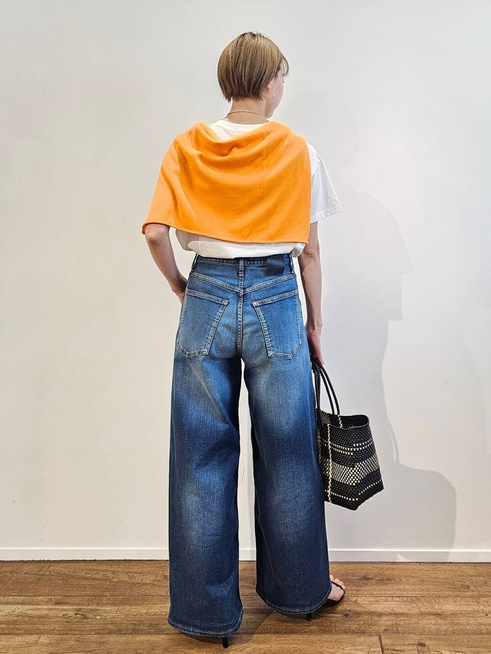 ブルー系のデニムパンツ、ブラック系のサンダル、その他のトートバッグを着用したレディースの春コーディネートの3枚目の写真