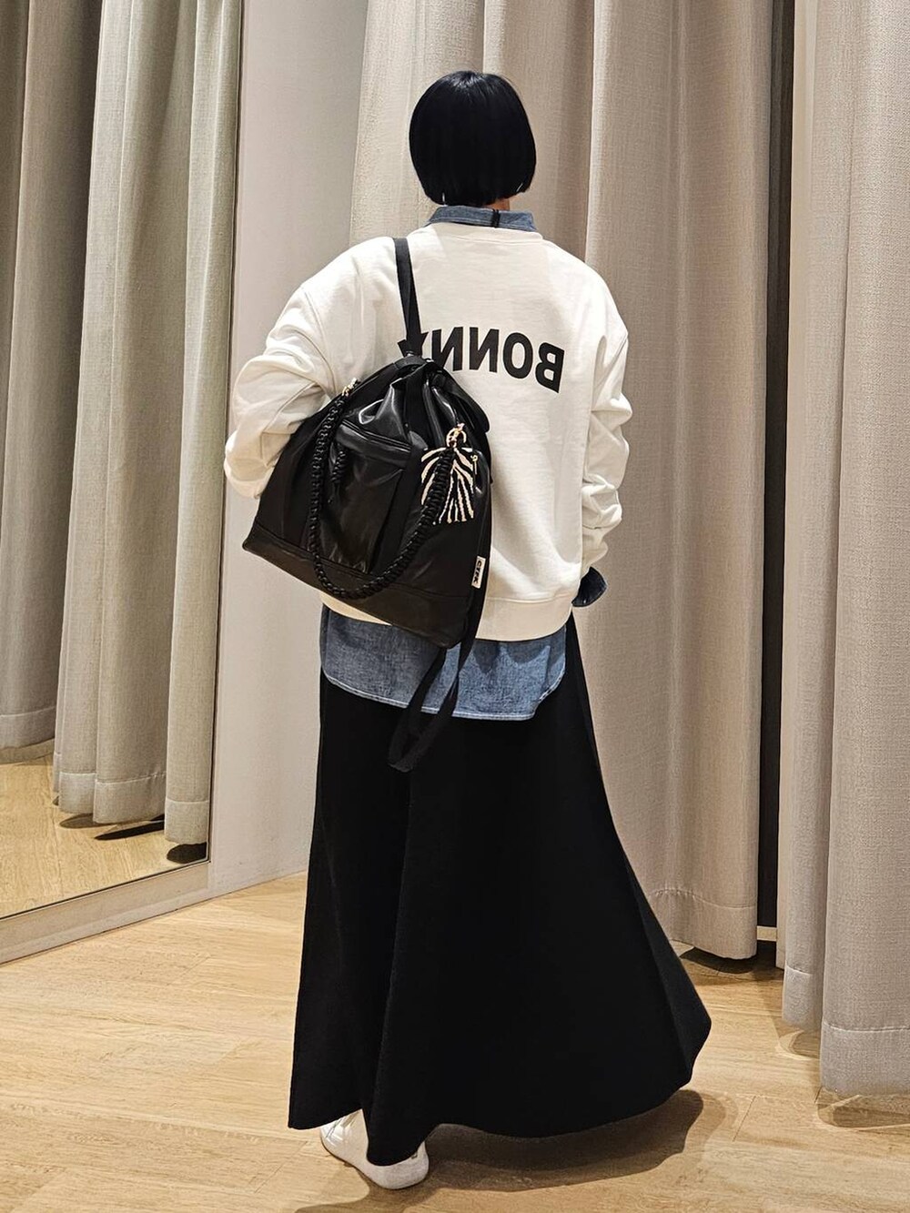 ブラック系のバックパック/リュック、ブラック系のスカート、ホワイト系のスウェットを着用したレディースの冬コーディネートの4枚目の写真