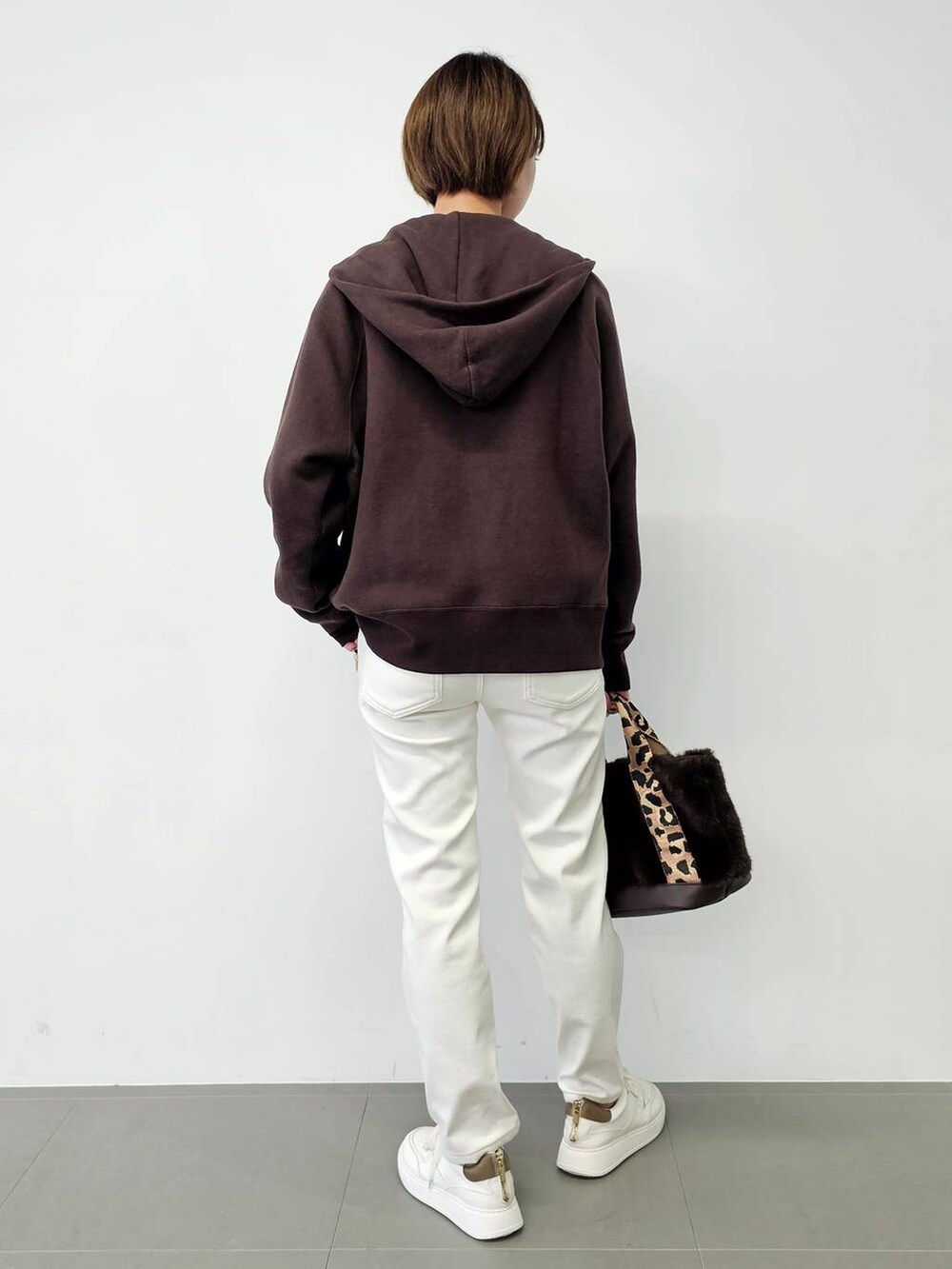 ホワイト系のデニムパンツ、ベージュ系のTシャツ/カットソー、ホワイト系のスニーカーを着用したレディースの秋コーディネートの3枚目の写真