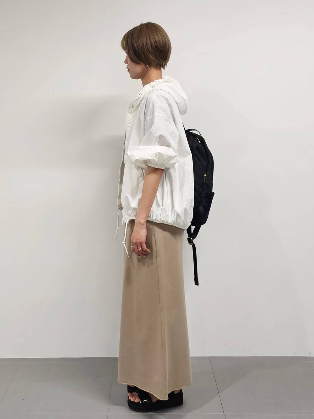 ブラック系のバックパック/リュック、ブラック系のサンダル、ベージュ系のスカートを着用したレディースの春コーディネートの2枚目の写真