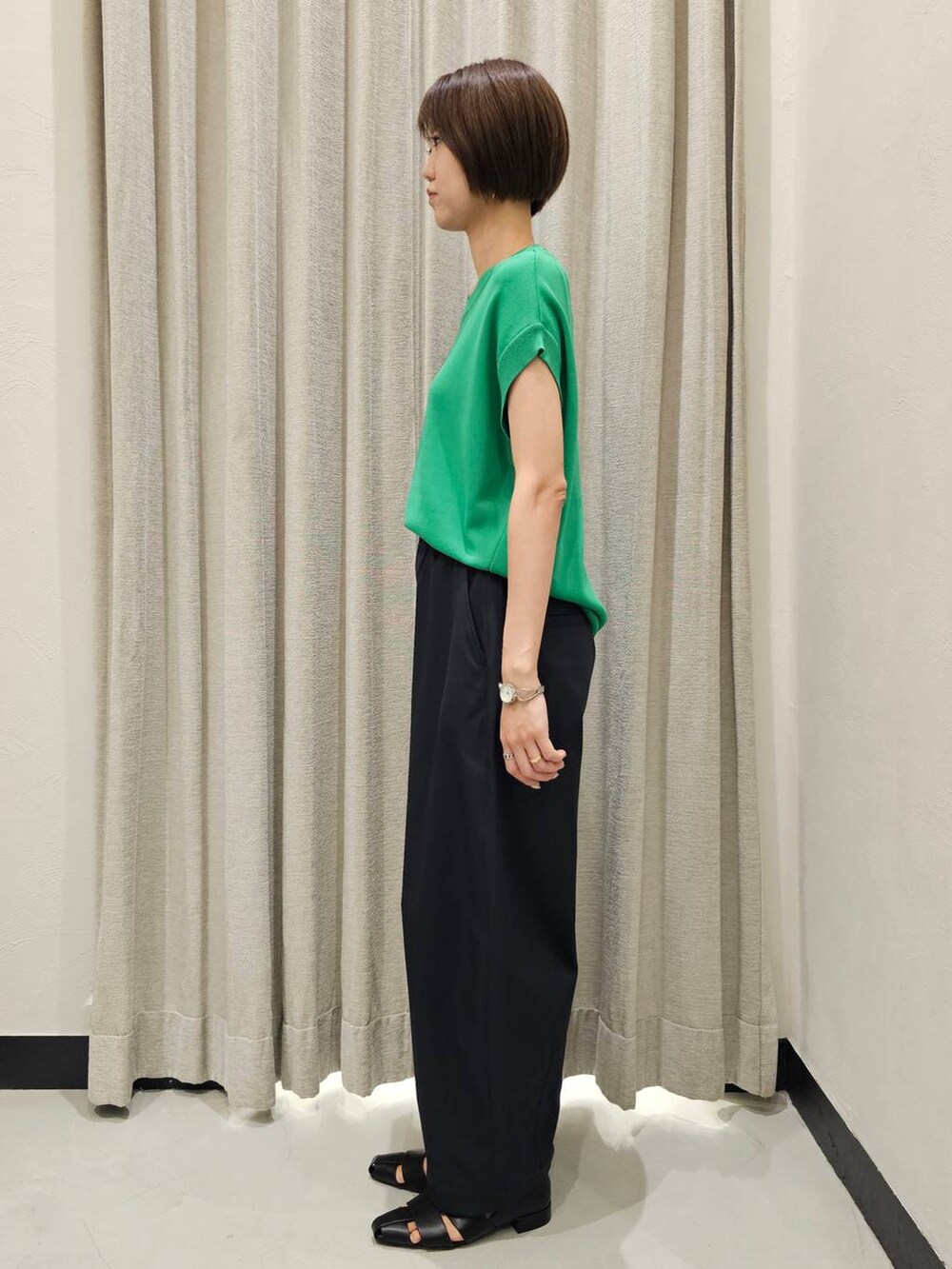 ブラック系のその他パンツ、ブラック系のパンプス、グリーン系のニット/セーターを着用したレディースの秋コーディネートの2枚目の写真