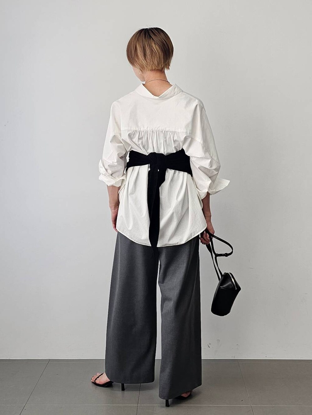 ブラック系のショルダーバッグ、ブラック系のサンダル、ホワイト系のシャツ/ブラウスを着用したレディースの夏コーディネートの4枚目の写真