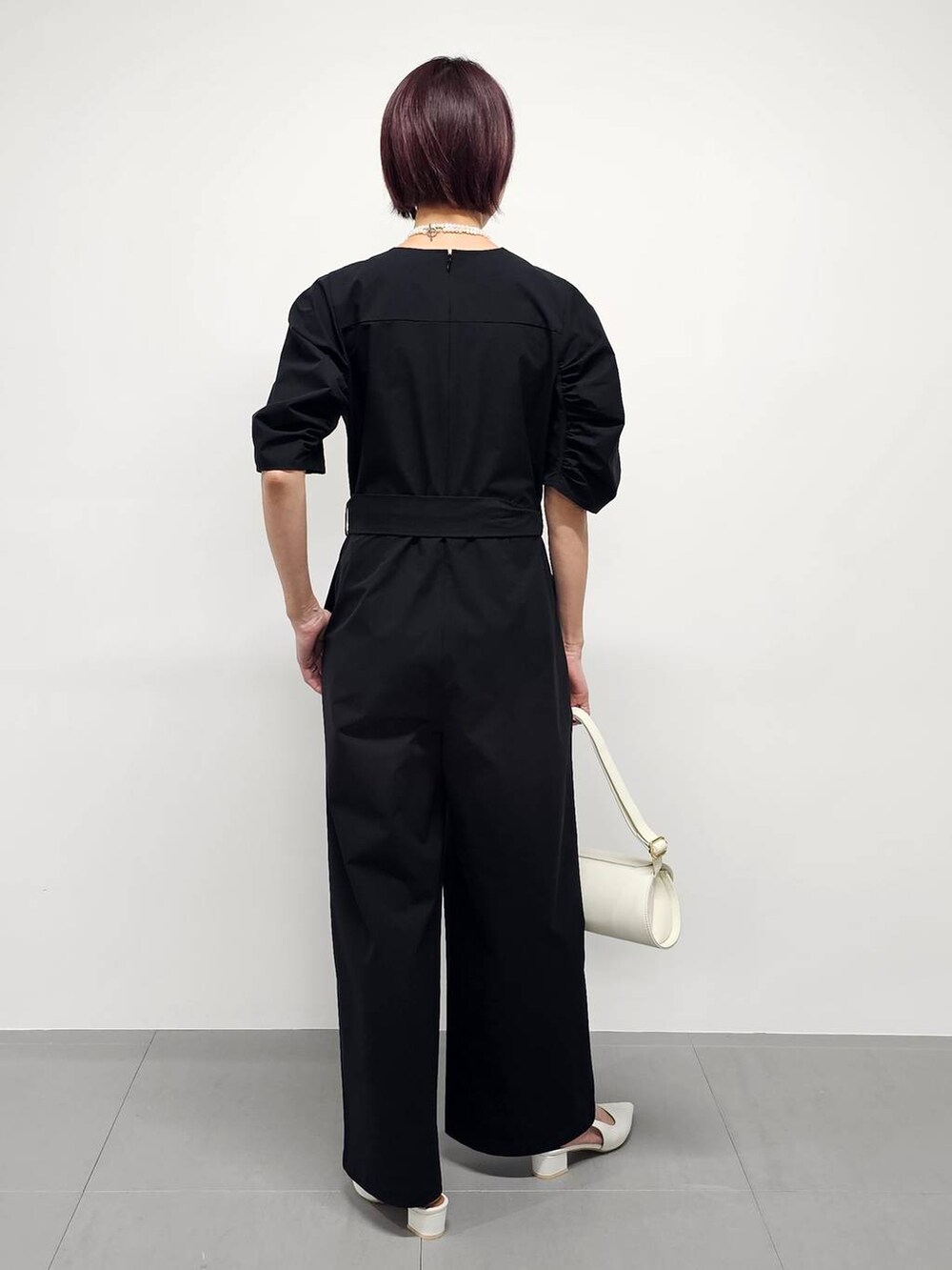 ブラック系のつなぎ/オールインワン、グレー系のテーラードジャケット、ホワイト系のパンプスを着用したレディースの冬コーディネートの6枚目の写真